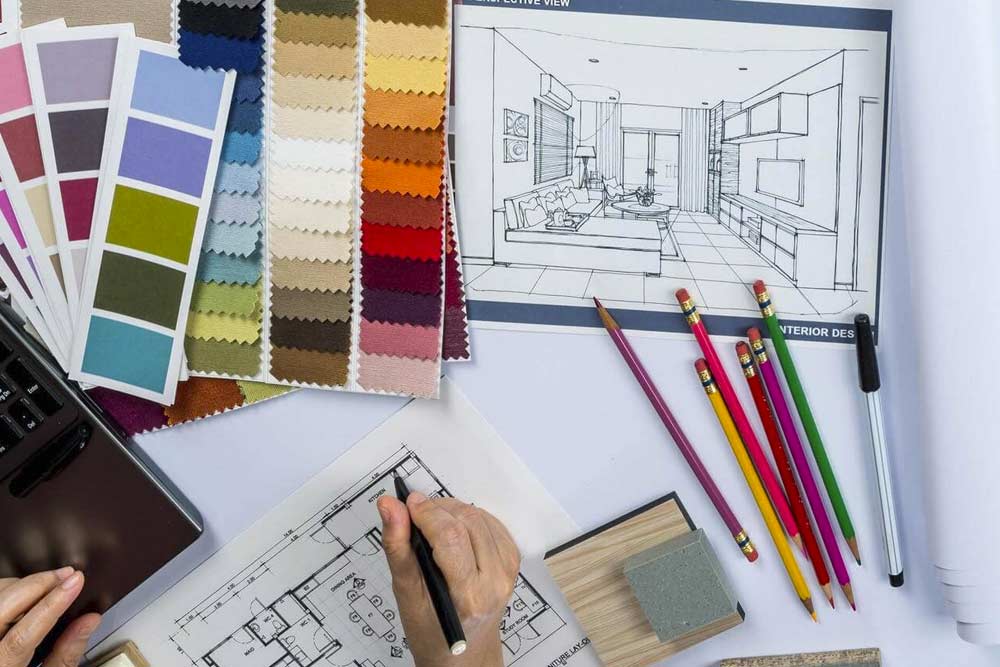 Planos de interiores, muestras de colores y lápices sobre una mesa