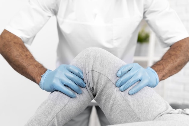 Profesional con guantes examinando la rodilla de una persona